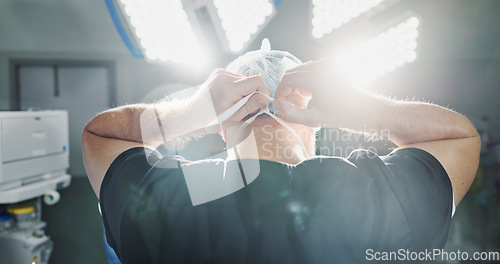 Image of Surgery, preparation and doctor tie mask in operating room for medical service, protection and operation. Healthcare ppe, safety scrubs and person with uniform for emergency, procedure and wellness