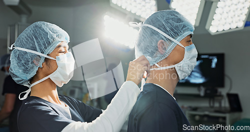 Image of Surgery, hospital and doctors tie mask in operating room for medical service, preparation and operation. Healthcare team, safety scrubs and people with uniform for emergency, procedure and protection