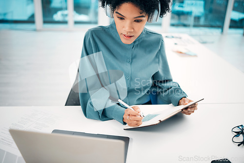 Image of Headphones, technology and woman writing notes in the office doing research for creative project. Notebook, laptop and professional female designer working, planning and listen to music in workplace.