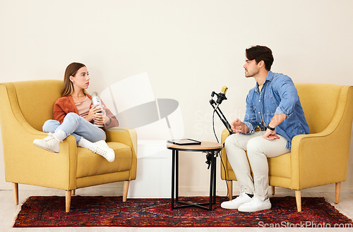 Image of Man, woman and mic for podcast, speaking or question in conversation, interview and lounge chair. Talk show, microphone and people together for broadcast, live streaming and tablet for social network