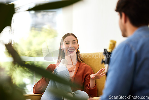 Image of Man, woman and microphone for podcast, speaking or question in conversation, interview and lounge chair. Talk show, mic and people together for broadcast, live streaming and happy on social network