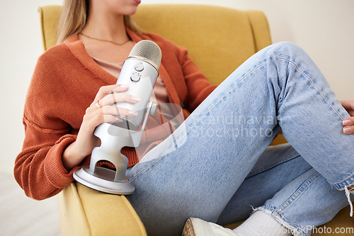 Image of Microphone, closeup and woman hosting a podcast on a chair by a wall in her modern home. Radio, broadcast and young female person hosting a journalism talk show in a recording space at her house.