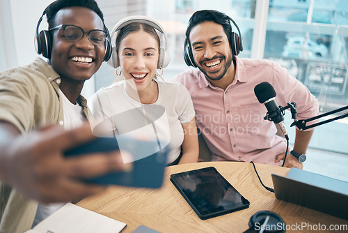 Image of Podcast, smile and group selfie of friends together bonding, live streaming and people recording broadcast in studio. Happy team of radio hosts take picture at table for social media or collaboration