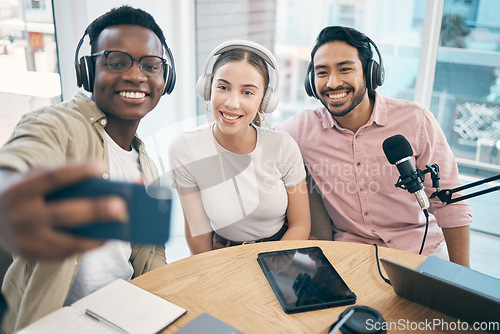 Image of Podcast, happy and group selfie of friends together, live streaming or people recording broadcast in studio. Team of radio hosts take photo at table for social media blog on headphones or microphone
