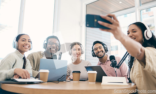 Image of Podcast, happy and group selfie of friends together, live streaming or people recording broadcast on headphones or mic in studio. Smile, team and radio hosts take photo at table for social media blog