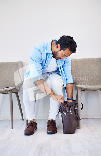 Image of Bag, search and man in waiting room for interview, hiring and recruitment with lost resume in briefcase. Stress, finding and person forget laptop or keys by mistake, frustration and worried in office