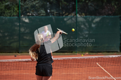 Image of Young girls in a lively tennis match on a sunny day, demonstrating their skills and enthusiasm on a modern tennis court.