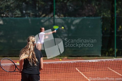 Image of Young girls in a lively tennis match on a sunny day, demonstrating their skills and enthusiasm on a modern tennis court.