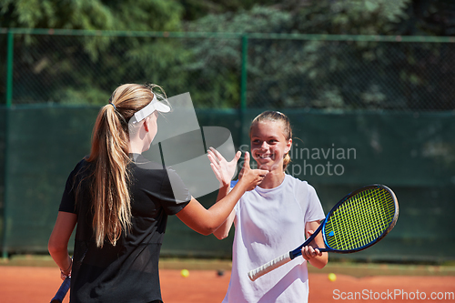 Image of Two female tennis players shaking hands with smiles on a sunny day, exuding sportsmanship and friendship after a competitive match.