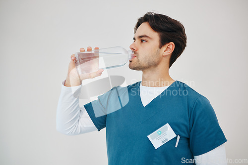 Image of Nurse drink water in bottle for health, wellness or body nutrition in studio isolated on a white background in hospital. Man, medical professional or hydration with liquid of thirsty surgeon on break