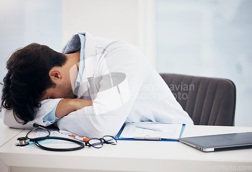 Image of Man, doctor and sleeping for break, relax or burnout on desk in mental health or mistake at hospital office. Tired male person or medical surgeon chilling in rest or asleep on work desk at clinic