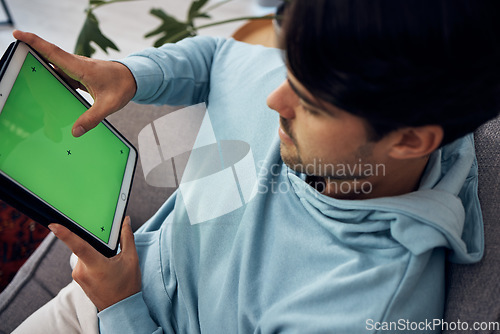 Image of Tablet, green screen and a man playing games on a sofa in the living room of his home from above. Technology, gaming and young gamer using a display or screen with tracking markers for entertainment