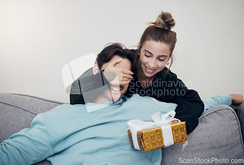 Image of Surprise, gift and couple on a sofa for birthday, celebration or anniversary at home. Gift, box and people in a living room with guess game for present, romance or congratulations gesture in a house