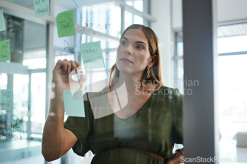 Image of Business woman, writing and glass board with thinking, ideas and sticky note with strategy for goals. Entrepreneur, brainstorming and problem solving for solution, process and development in office