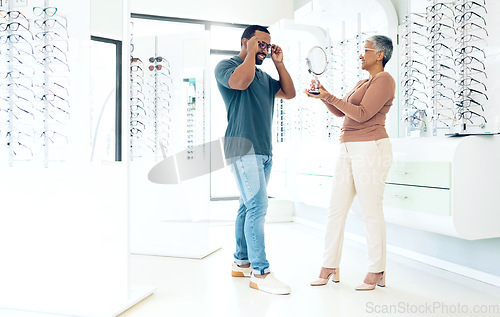 Image of Mirror, glasses and optician help happy man in store for choice of lens, frame and consultation. Smile, reflection and mature optometrist with patient for spectacles, healthy vision and ophthalmology