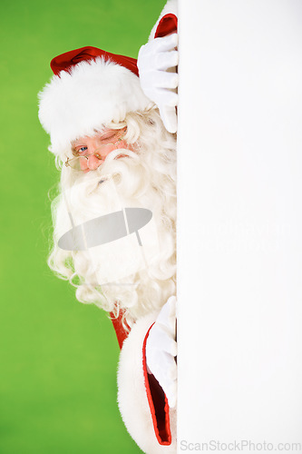 Image of Santa claus, hiding and wall portrait for Christmas celebration, mockup space or wink. Male person, secret peek and emoji face for festive seasons or holiday, green studio background or signboard