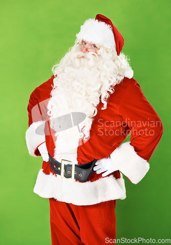 Image of Santa claus, hands and hips in studio portrait for holiday celebration, festive season or gift giving. Father Christmas, face and costume suit for winter vacation fun, on green background for joy