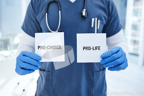 Image of Closeup, doctor and abortion with option, card and healthcare in a hospital, policy and law. Zoom, person and medical professional with poster, choice and paper with nurse and decision in a clinic