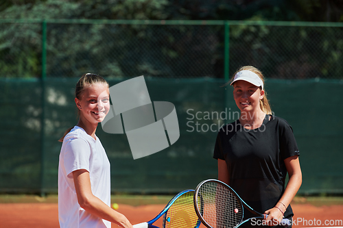 Image of Two female tennis players shaking hands with smiles on a sunny day, exuding sportsmanship and friendship after a competitive match.