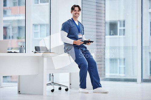Image of Hospital portrait, tablet and happy man, doctor or relax nurse research, typing or search medical database, info or data. Online medicine stats, healthcare clinic and surgeon sitting on office desk