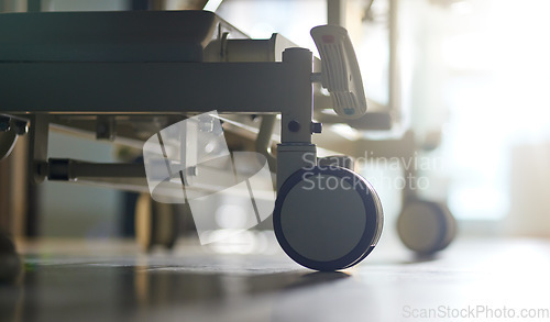 Image of Hospital, bed and wheels of stretcher on floor, ground or interior of empty clinic with equipment. Healthcare, transport and closeup of medical wheeling chair or gurney in medical furniture and room