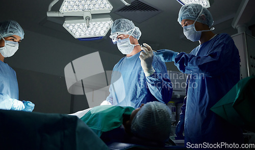 Image of Teamwork, tools or doctors in surgery emergency procedure or healthcare operation in hospital at night. Giving, trust or surgeon in face mask or gloves helping in dark theatre room in medical clinic