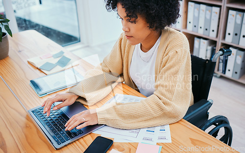 Image of Office, laptop and woman in wheelchair typing at a desk with company report and internet research. Online, computer and female person with a disability and web work on a website with app analysis