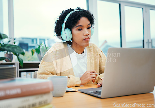 Image of Serious, headphones and business woman on laptop working in creative startup office. Radio music, computer and professional designer planning at desk, listen to audio podcast online or reading email