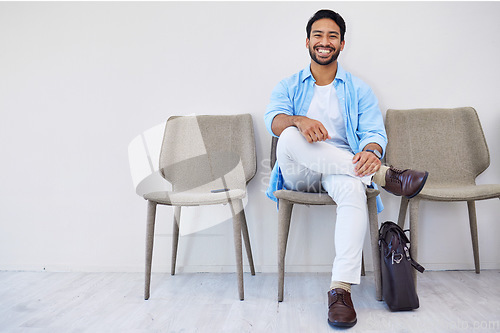 Image of Smile, waiting and man in the office for recruitment meeting with human resources for hiring. Confidence, professional and person sitting on a chair for job interview in hallway in modern workplace.