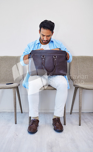 Image of Interview, man and job in waiting room, briefcase and looking for cv in bag by wall background. Business person, search and anxious to find resume, human resources and hiring or marketing opportunity