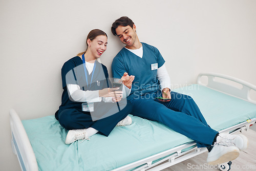 Image of Doctors, smartphone and break on hospital bed, relax and happy from healthcare service, job and career. Nurse, man and woman for rest, shift and employee for social media, memes and communication