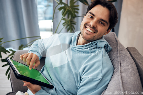 Image of Portrait, tablet and green screen with a man gaming on a sofa in the living room of his home to relax. Technology, smile and happy young gamer using a display with tracking markers in his apartment