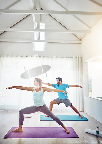 Image of Couple, yoga and stretching in studio workout, exercise and holistic training with balance, pilates or fitness. People or personal trainer in warrior pose for wellness, health and learning together