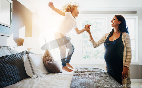 Image of Family, pregnant woman and her son jumping on the bed while in their home together. Flare, love or smile and a boy child playing in the bedroom with his happy parent for freedom, fun or bonding