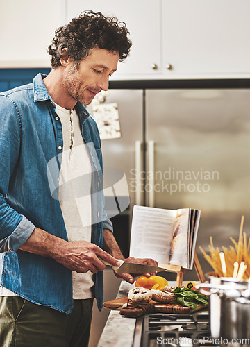 Image of Recipe, food and man cutting vegetables in the kitchen for diet, healthy or nutrition dinner. Book, cooking and mature male person from Canada chop ingredients for a supper or lunch meal at home.