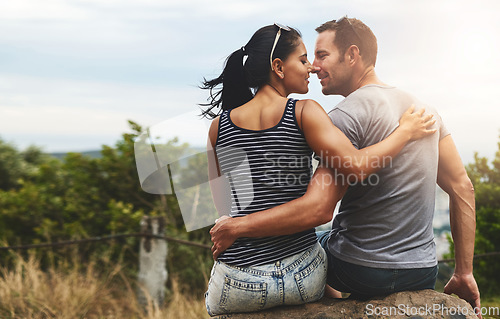 Image of Back view, love or happy couple hug in park for date, freedom or care in nature with peace or bond. Eye contact, romantic man or woman on rock or outdoor holiday vacation together to relax or travel