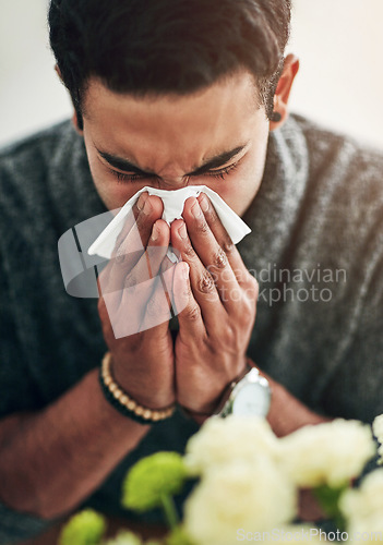 Image of Face, hand and blowing nose with a man using a tissue in his home for relief from allergy symptoms. Sick, cold or flu disease and a young person ill with a virus due to bacteria, pollen or hay fever