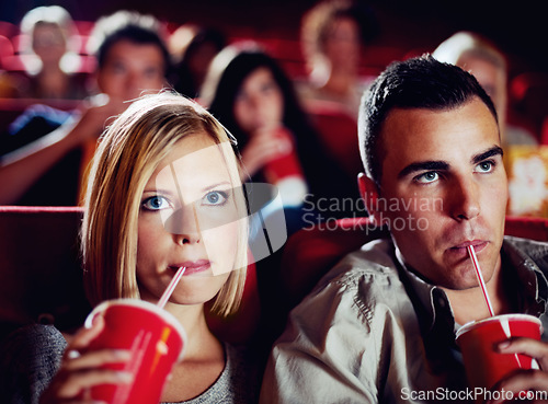 Image of Cinema, movie and couple with drink, watching film and concentration on romantic evening together. Date night, man and woman in theater with soda, attention and sitting in auditorium to relax at show