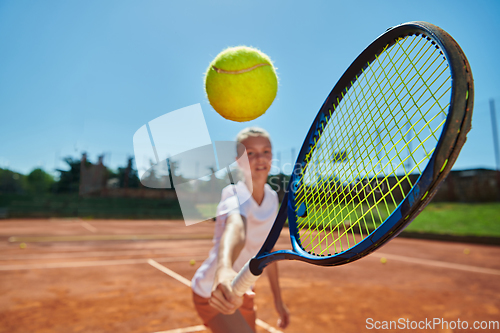 Image of Close up photo of a young girl showing professional tennis skills in a competitive match on a sunny day, surrounded by the modern aesthetics of a tennis court.