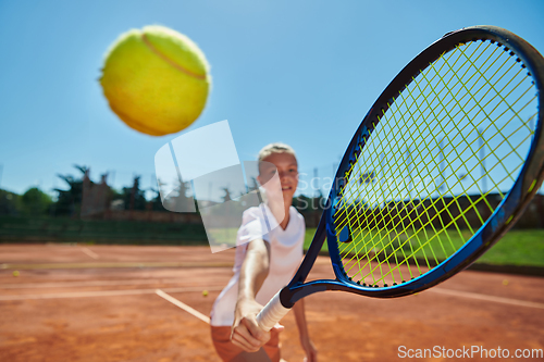 Image of Close up photo of a young girl showing professional tennis skills in a competitive match on a sunny day, surrounded by the modern aesthetics of a tennis court.