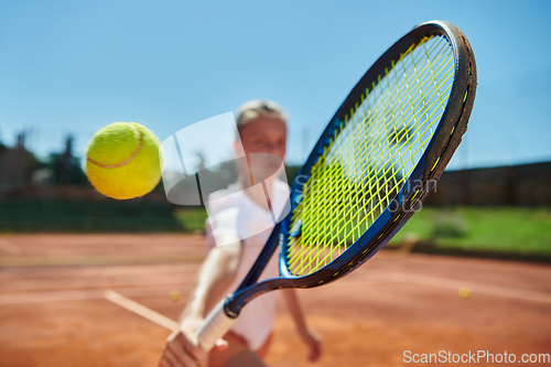 Image of Close up photo of a young girl showing professional tennis skills in a competitive match on a sunny day, surrounded by the modern aesthetics of a tennis court.