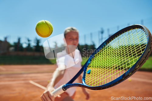 Image of Close up photo of a young girl showing professional tennis skills in a competitive match on a sunny day, surrounded by the modern aesthetics of a tennis court.