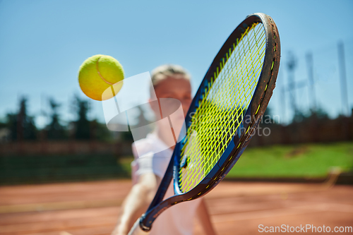 Image of Close up photo of a young girl showing professional tennis skills in a competitive match on a sunny day, surrounded by the modern aesthetics of a tennis court.