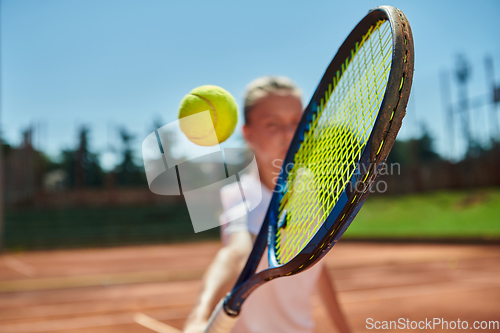 Image of Close up photo of a young girl showing professional tennis skills in a competitive match on a sunny day, surrounded by the modern aesthetics of a tennis court.