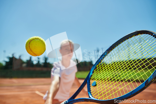 Image of Close up photo of a young girl showing professional tennis skills in a competitive match on a sunny day, surrounded by the modern aesthetics of a tennis court.