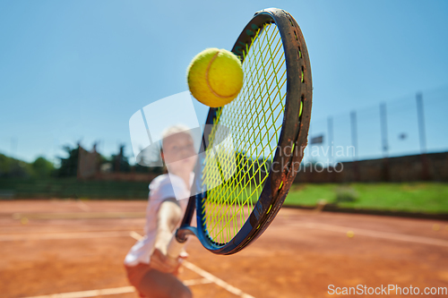 Image of Close up photo of a young girl showing professional tennis skills in a competitive match on a sunny day, surrounded by the modern aesthetics of a tennis court.