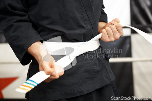 Image of Man, hands and white belt in karate of martial arts beginner, training or discipline at dojo. Closeup of male person tying gi or ranking in self defense, arena or professional fighting sport match