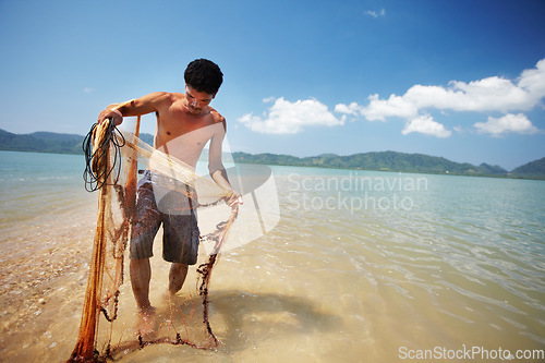 Image of Fisherman, sea and man with net working, nature and labor with fishing in Thailand and tropical island location. Ocean, job and rope with worker in water to catch fish and beach with environment