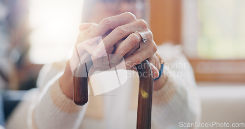 Image of Walking stick, hands and senior woman with a disability in home, apartment or retirement with support for injury. Elderly, closeup or person with wood cane to help balance or mobility with arthritis