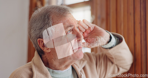 Image of Depression, sad or nostalgia with a senior man looking through a window in his home during retirement. Thinking, memory or the past with an elderly person feeling lonely in the living room of a house